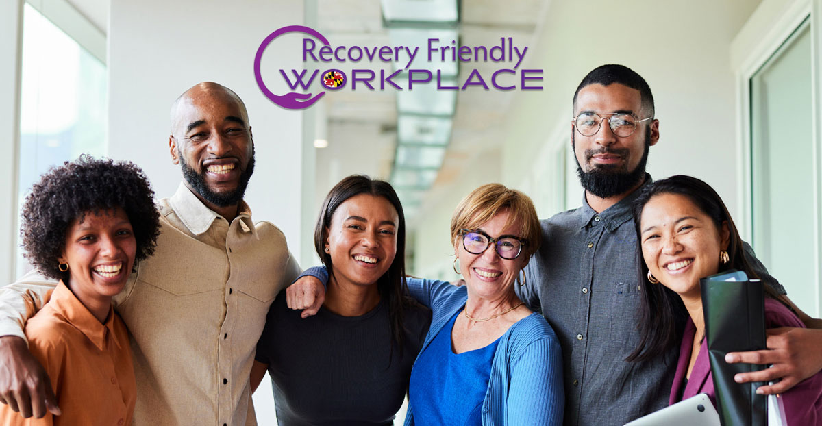 recovery friendly workplace logo and 6 workers stand in  an office