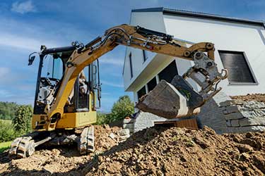 Excavator equipment digging near house