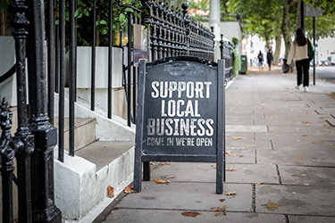 City sidewalk with folding we're open sign