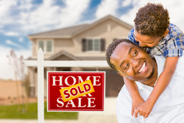 man with son in front of house with a SOLD sign